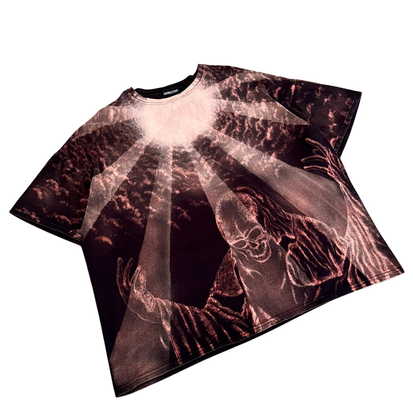 A short-sleeve t-shirt featuring a dramatic graphic print of a figure with outstretched hands under radiant light rays, rendered in metallic rose gold and dark brown tones on a white background.
