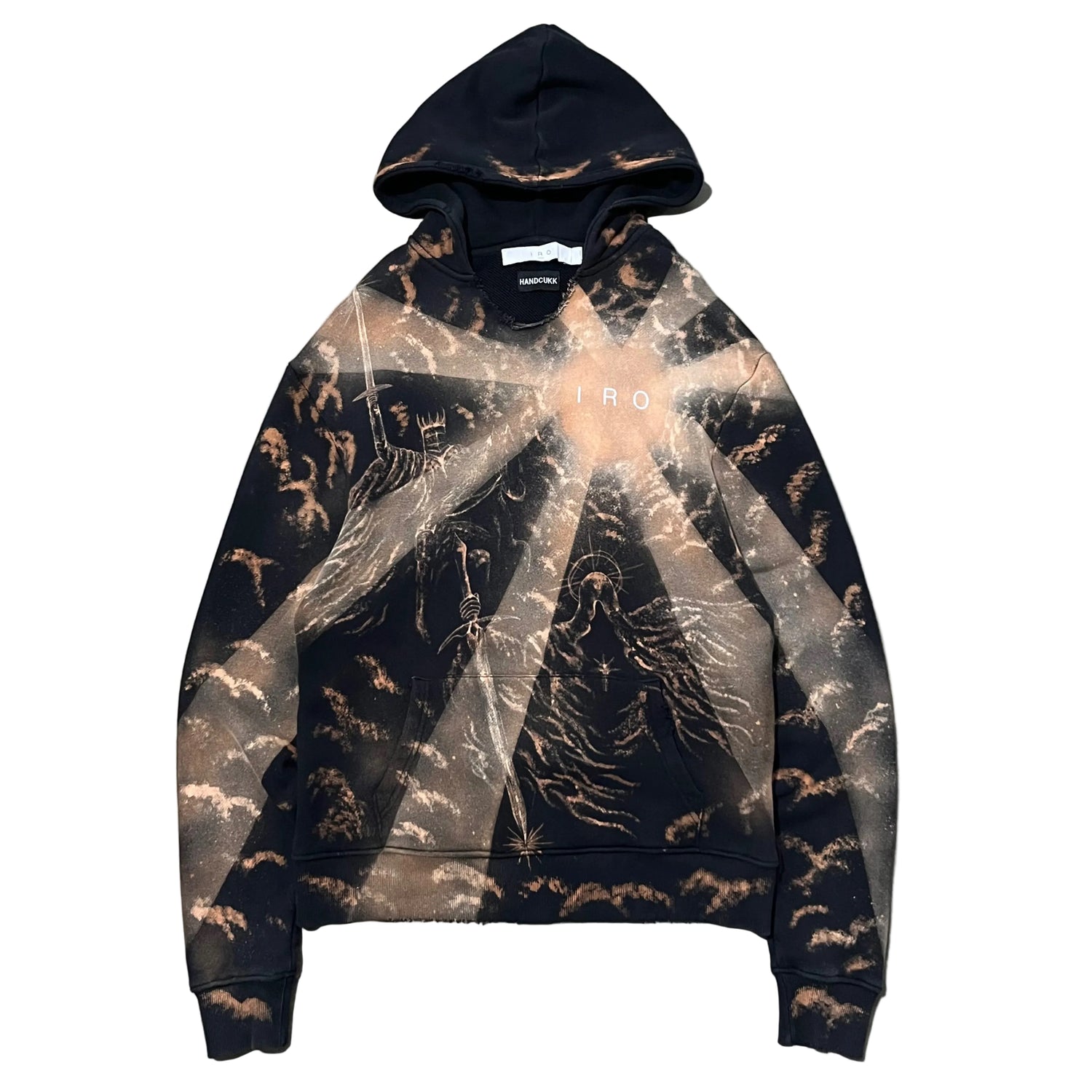 A black pullover hoodie hand painted bleach art with a brown and beige celestial cloud pattern, laid flat on a textured gray concrete surface. The hoodie features a subtle semi-transparent overlay graphic of a starry sky and has 'IRO' printed in white across the chest.