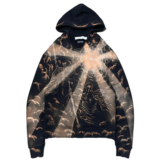 A black pullover hoodie hand painted bleach art with a brown and beige celestial cloud pattern, laid flat on a textured gray concrete surface. The hoodie features a subtle semi-transparent overlay graphic of a starry sky and has 'IRO' printed in white across the chest.