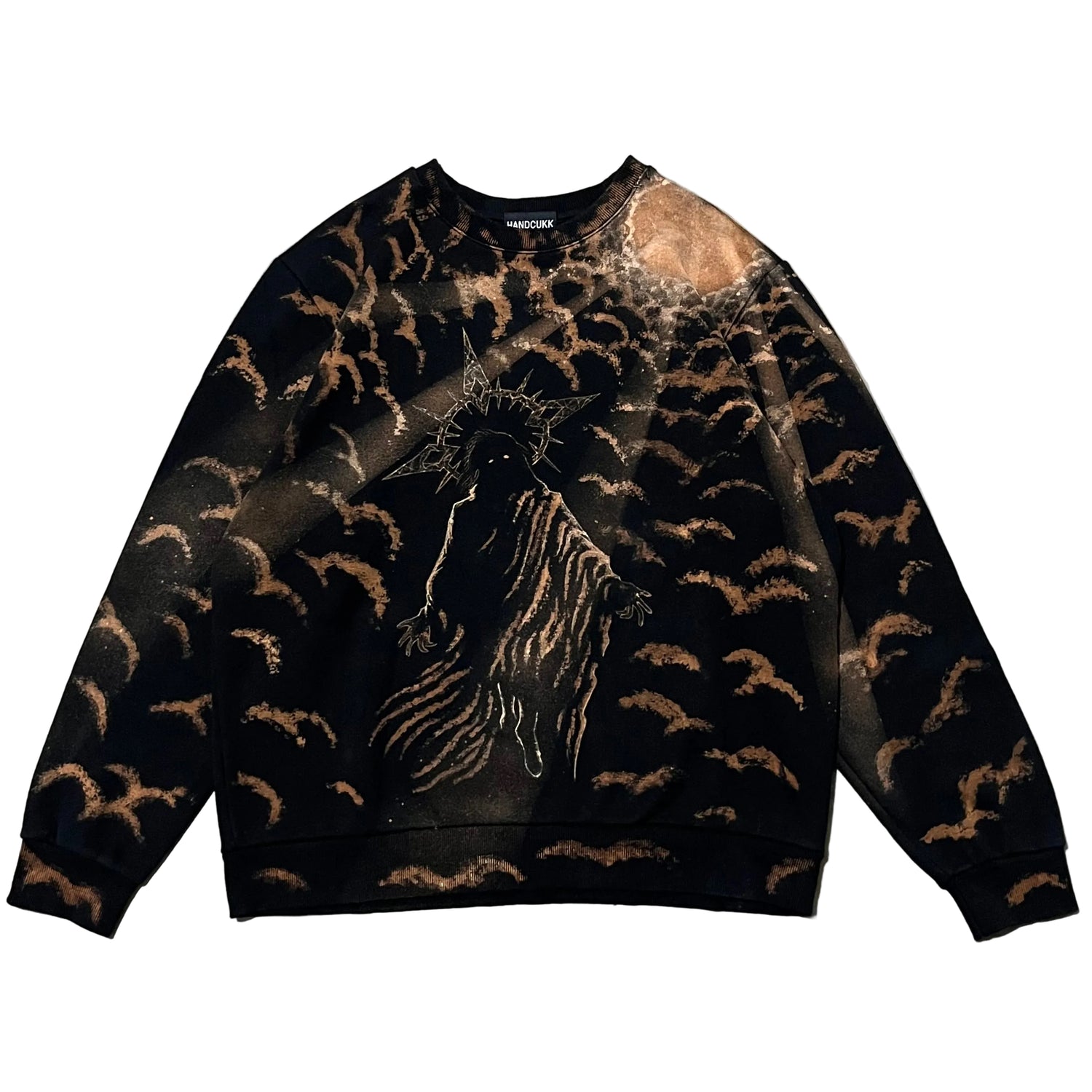 A black crewneck sweatshirt featuring a graphic print of a crowned figure in the center, surrounded by a swirling pattern of brown bat-like silhouettes, laid flat on a textured gray concrete surface.