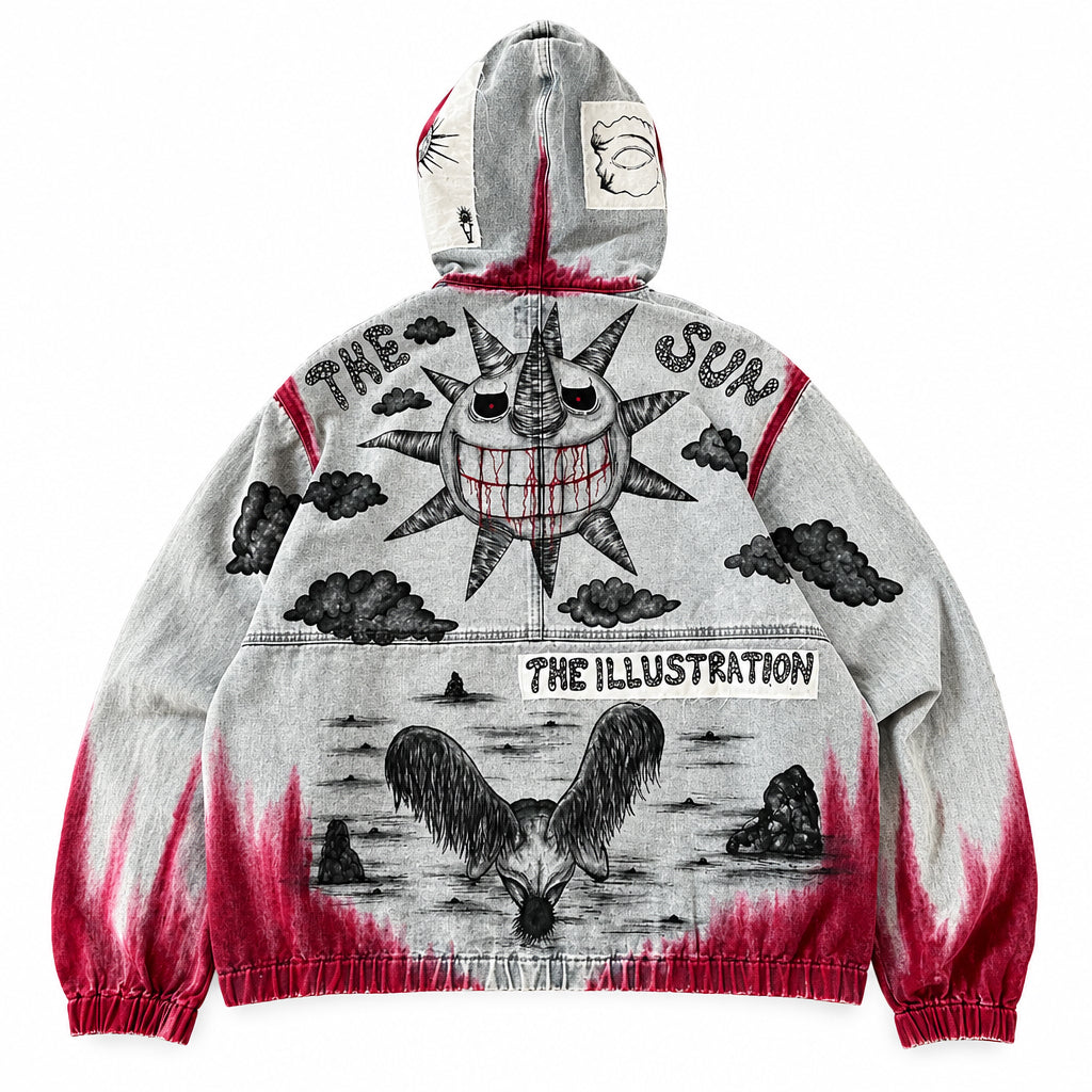 A heather blue vintage wash hooded denim jeans jacket with a detailed black ink illustration and red acid-wash accents, laid flat on white background. The graphic features a sun, clouds and the text 'THE SUN' and ‘THE ILLUSTRATION'.